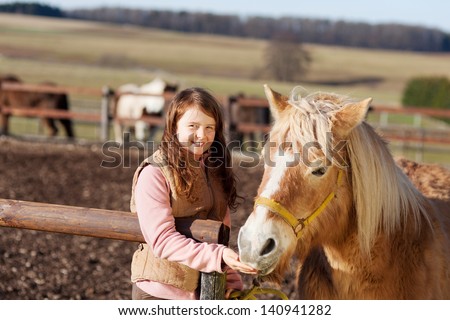 Portrait of a happy smiling girl feeding her horse treats