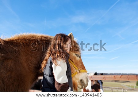 Pretty girl leading her horse in the paddock on a bright sunny day