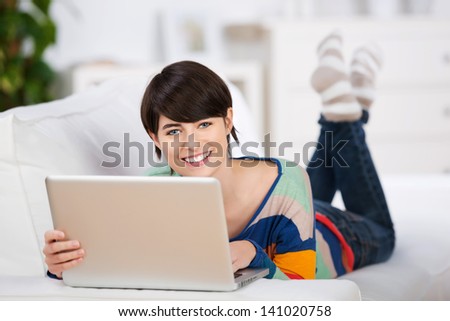 Young woman relaxing on couch and searching in laptop