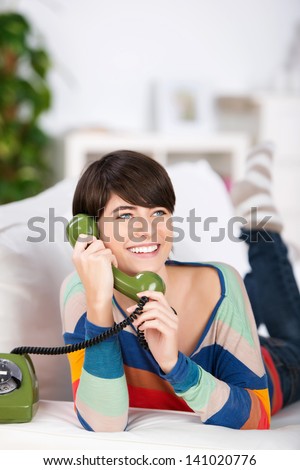 Smiling woman talking through the green telephone at home