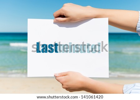 Closeup of woman\'s hands holding placard with Last Minute sign on beach
