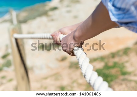 Closeup of woman\'s hand pulling rope of railing at beach
