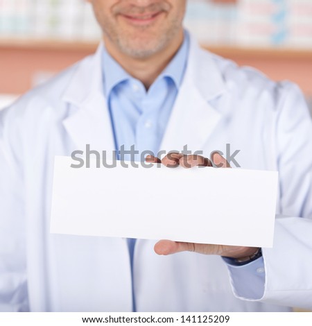 Smiling pharmacist showing the white envelope over the medicine background