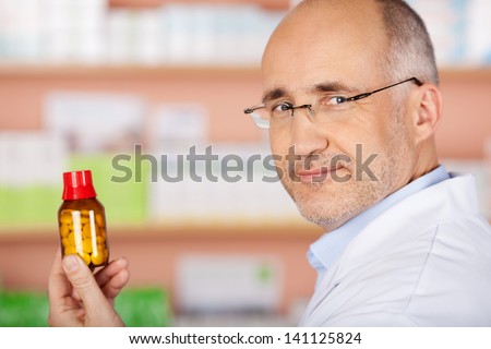 Mature male pharmacist shows the medicine at the drugstore