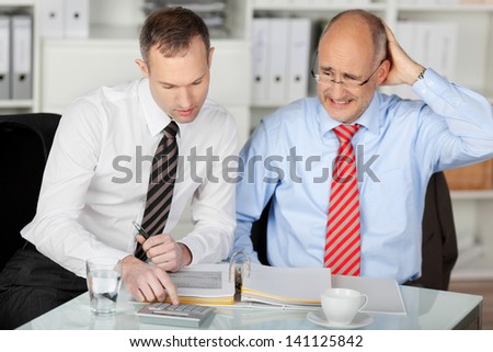 Portrait of businessman consulting his mad partner at desk in office