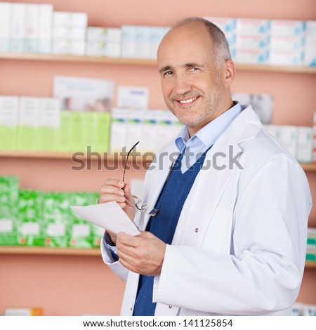 Smiling pharmacist standing in front of medicine check the prescription