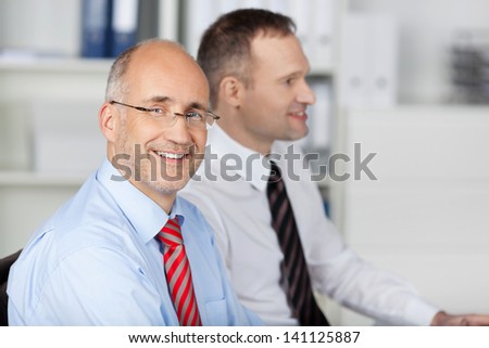 Portrait of two businessmen talking to someone inside the office