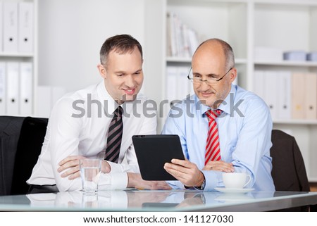 Two businessmen searching something using tablet computer