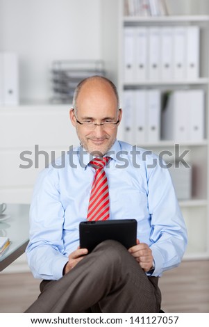 Bald businessman browsing the internet through tablet computer