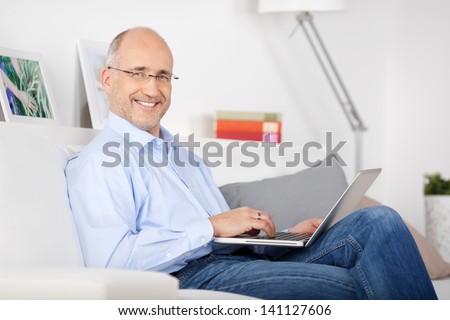 Smiling man sitting on the couch and browsing the internet