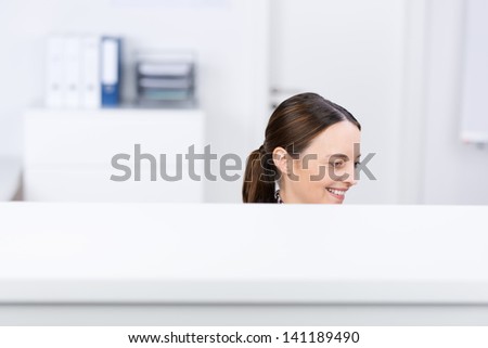Mid adult smiling businesswoman in office cubicle