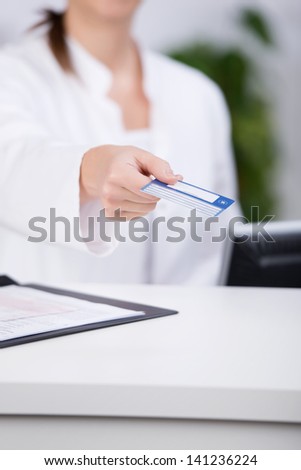 Midsection of receptionist giving credit card at counter in hospital