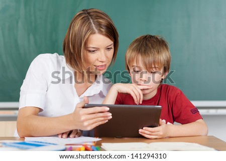 Teaching a boy with a tablet in classroom