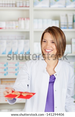 Smiling female pharmacist chemist giving a red card to someone
