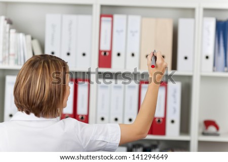 Female secretary write something on the stack of files at the shelf