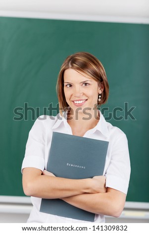 Beautiful teacher holding a lesson plan inside the classroom