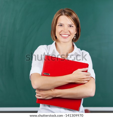 Smiling teacher holding red portfolio over the green background