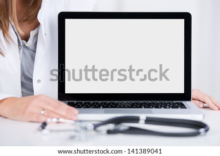 Midsection of female doctor with laptop at desk