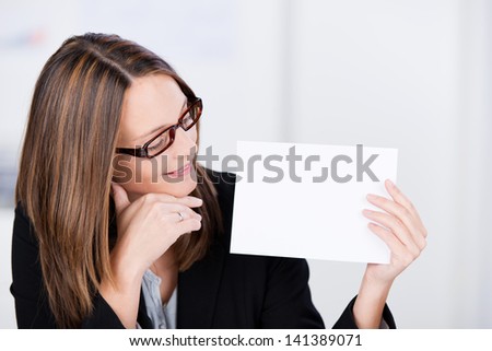Mid adult smiling businesswoman looks at white paper in office - copy space for you text