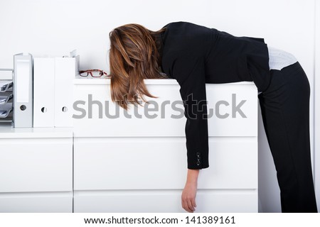 Side view of businesswoman sleeping on counter in office