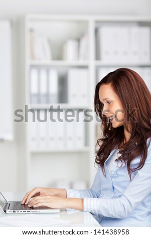Smiling woman sitting thinking in an office chair as she mulls over a new idea in her mind