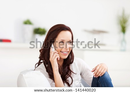 Woman listening to a conversation on her mobile phone while relaxing on a sofa at home