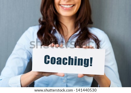 Smiling Woman Showing White Card With Coaching Word In A Close Up Shot