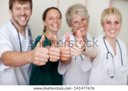 Portrait of happy doctors team showing thumbs up at clinic