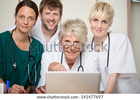 Confident male and female doctors with laptop in hospital