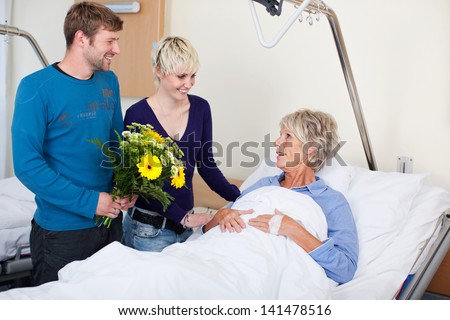 Happy children with flowers visiting mother in hospital