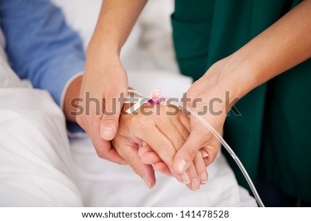 Closeup Of Nurse Holding Patients Hand In Hospital