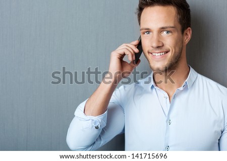 Closeup of happy young man using mobile phone against blue background