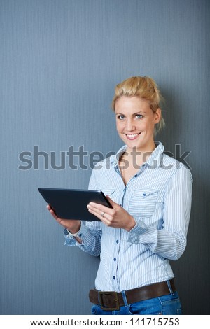 Smiling young female executive using digital tablet against gray background