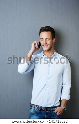 Happy Young Man Using Mobile Phone Against Blue Background