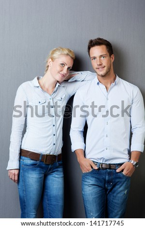 Cool young man and woman standing against gray background