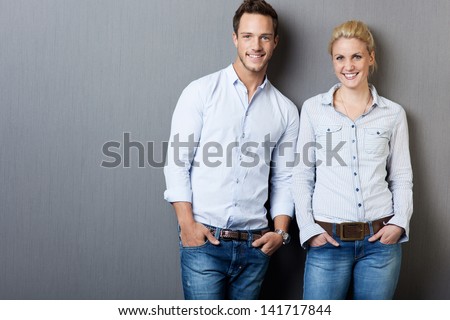 Portrait of a smart young man and woman standing against gray background