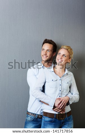 Smart young man and woman looking up and standing against gray background