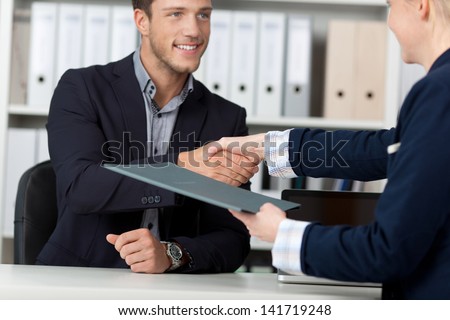 Happy businessman shaking hands with a female interviewer in office