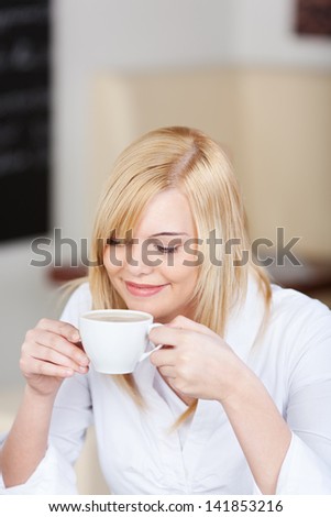 Young beautiful businesswoman having coffee in office cafe