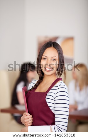 young waitress with red apron in cafe holding menu