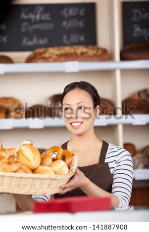 young saleswoman at work in bakery with shelves in background