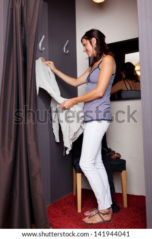 Full length of mid adult woman looking at dress in changing room