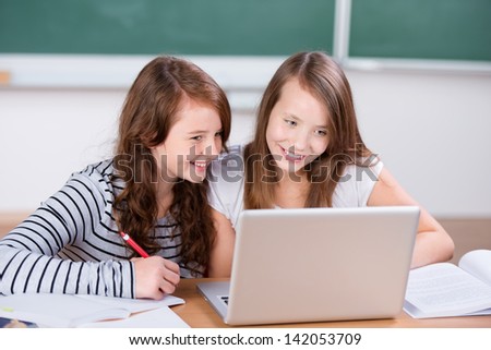 Portrait of two girls studying in front of laptop at the classroom