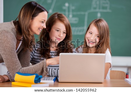 Portrait of teacher and students looking something at the laptop