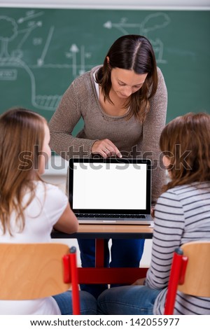 Female teacher teaching her two female students in front of laptop