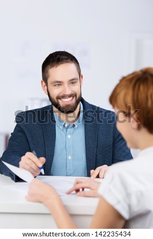 Young businessman explaining documents to female co worker at office desk