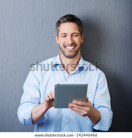 Portrait of smiling mature businessman using tablet computer against blue wall