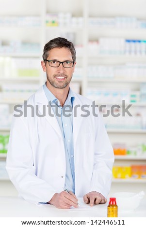 Mature confident male pharmacist at pharmacy counter