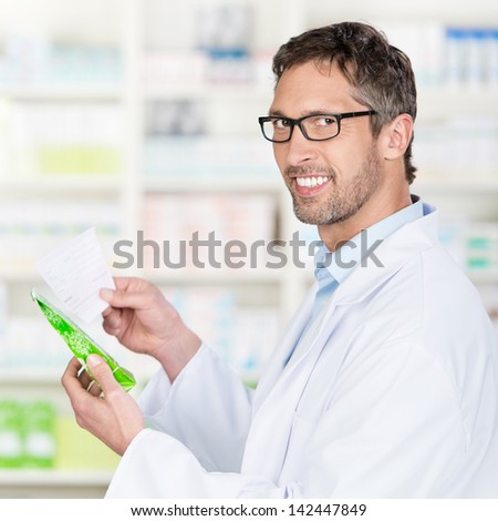 Portrait of mature male pharmacist holding prescription paper and product in pharmacy