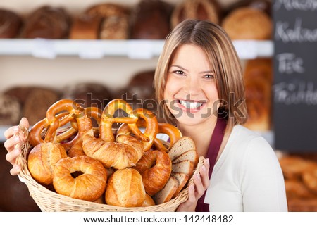 Smiling Bakery Assistant Holding Up A Collection Of Assorted Freshly Baked Rolls On Display In A Wicker Basket